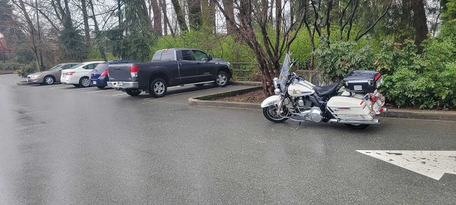three cars pulled over by a police motorcycle in a parking lot
